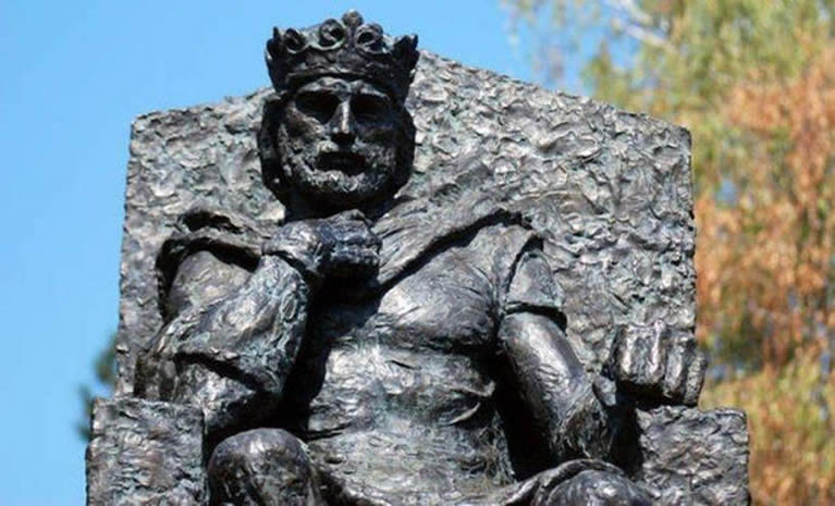 Realističan prikaz Kralja Tvrtka I Kotromanića, prvog bosanskog kralja, kako sjedi na prijestolju odjeven u kraljevske haljine s krunom na glavi i žezlom u ruci. U pozadini se nalazi srednjovjekovni dvor s kamenim zidovima i zastavama s grbom loze Kotromanića, stvarajući svečanu i povijesnu atmosferu.